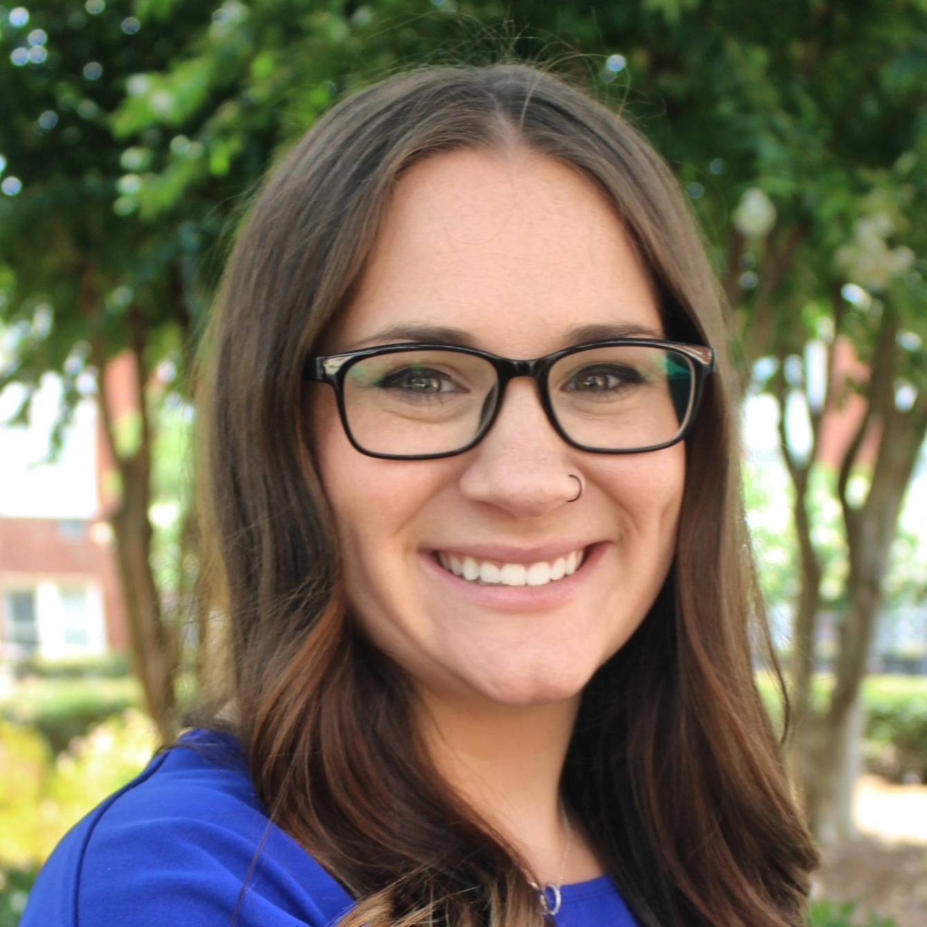 woman in blue smiling with glasses