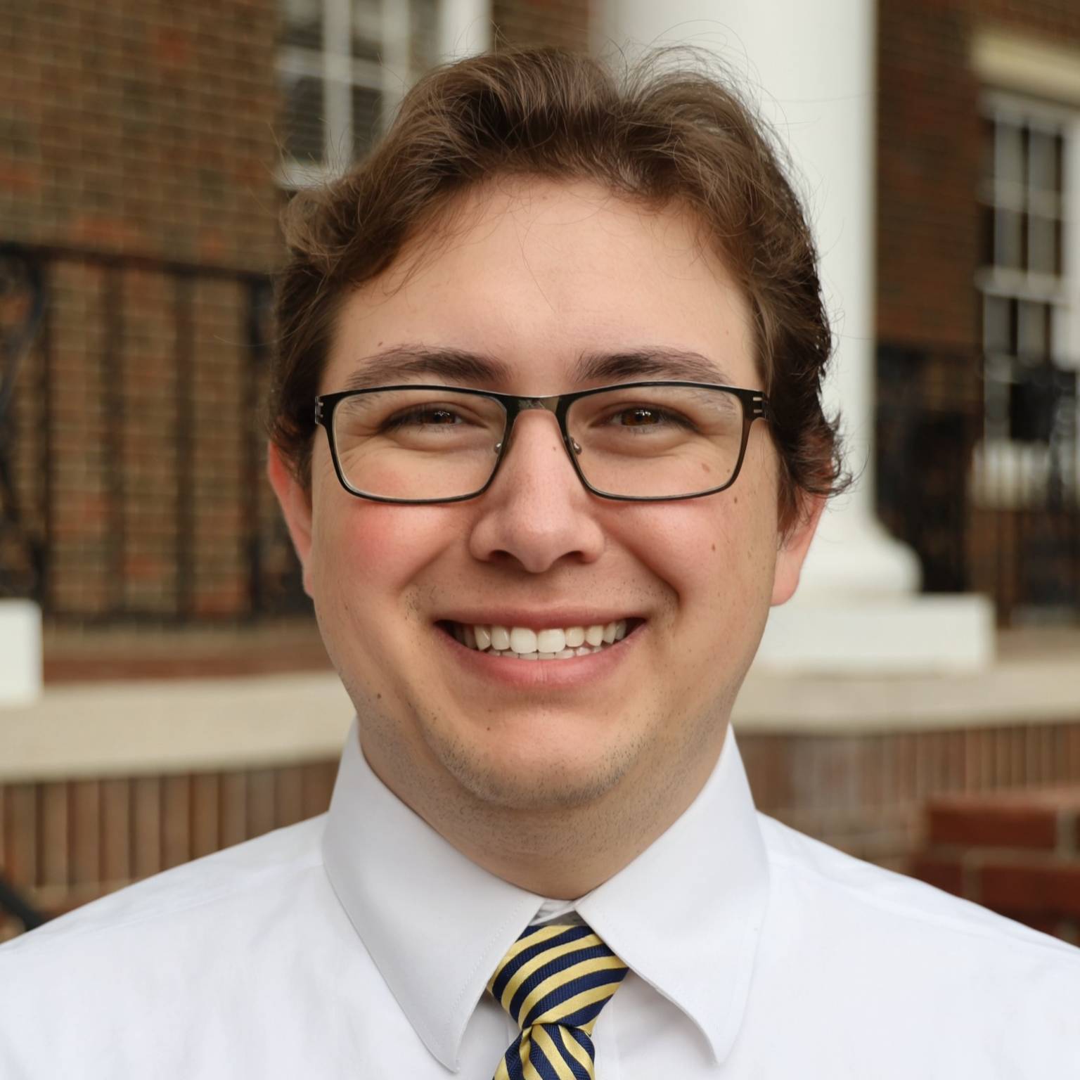 man in white shirt with tie and glasses smiling